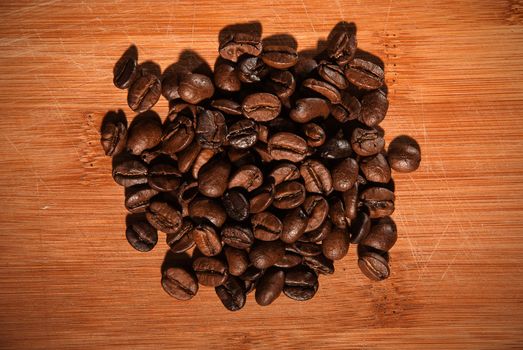 Bunch of fresh coffee beans on wooden table.