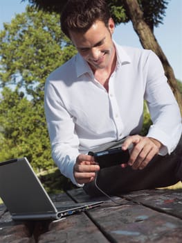 A smiling man with laptop outdoor 