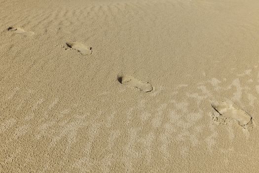 Footprint on a sand, a person on a jorney and walking alone