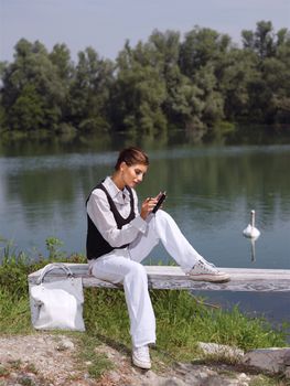Beautiful young woman using PDA outdoors 