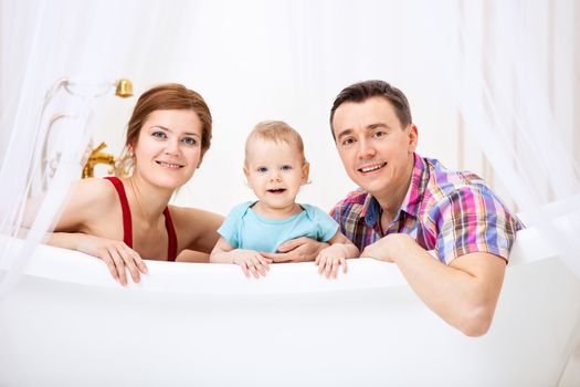 Happy young couple with son sitting in bath