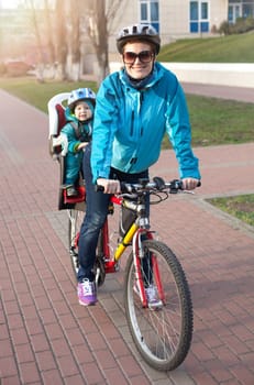 Caucasian young woman on a bicycle with little son behind his mother