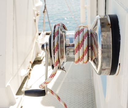White and red rope on winch with hand crank on a vessel