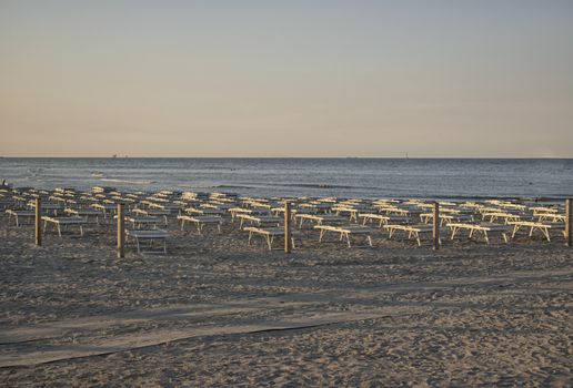 Deckchairs and umbrellas  on the seaside near the harbour channel of Cervia in Northern Italy on the Adriatic Sea