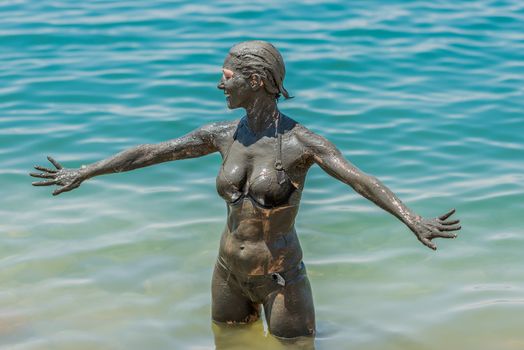 one caucasian woman applying dead sea mud body care treatment in jordan