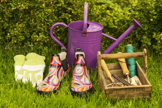 Ready for work  in the garden, gloves, boots, watering can and a basket with garden tools