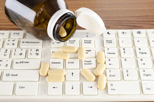 pills on keyboard computer on wooden background concept technology addiction