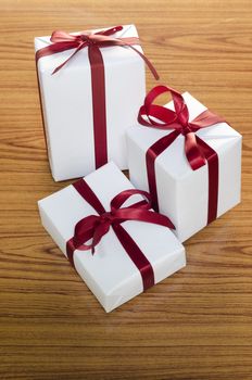 white gift box and red ribbin on wood background