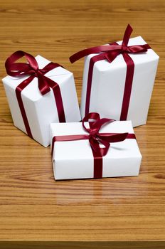 white gift box and red ribbin on wood background