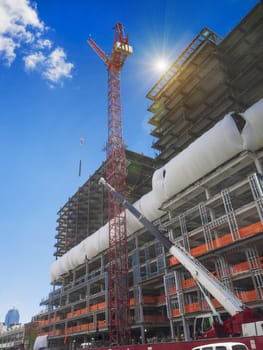 New building construction site with giant crane aligning steel beams