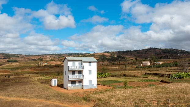 A two story white house next to a small white house in the middle of a beautiful landscape in Madagascar