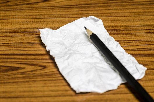 paper scrap with pencil on wood background