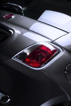 Detail of the boot and red covering on the taillight of a small compact hatchback car, low angle closeup
