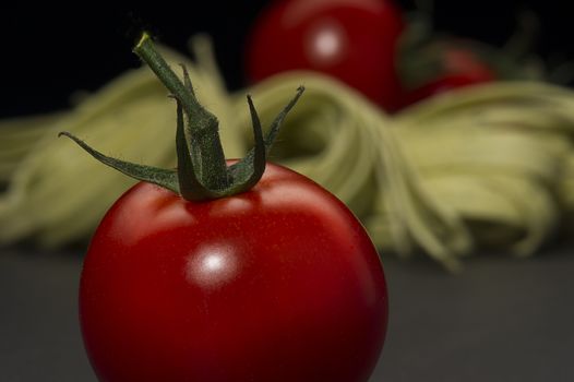 Ripe farm fresh juicy tomato with a green stalk for cooking in an Italian pasta recipe on a dark kitchen counter