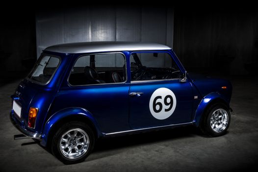 Iconic blue Mini Cooper , Austin or Morris, in a parking area with a 69 decal on the door, a popular economic two-door car introduced by BMC in the 1959 that went out of production in 2000