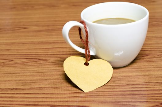 coffee cup with heart tag on wood background
