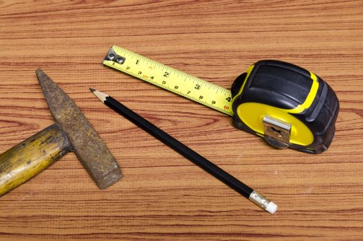 hammer measuring tape and pencil concept tools on wood background