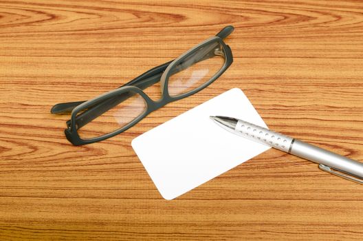 business card and pen with glasses on wood background