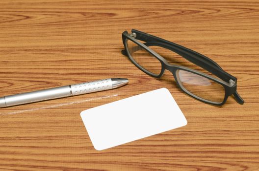 business card and pen with glasses on wood background