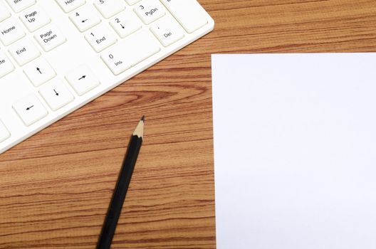 keyboard computee white paper and black pencil on wood background