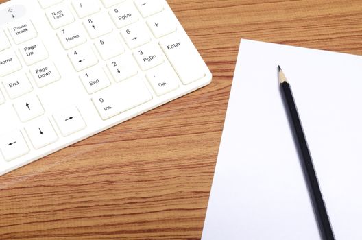 keyboard computee white paper and black pencil on wood background