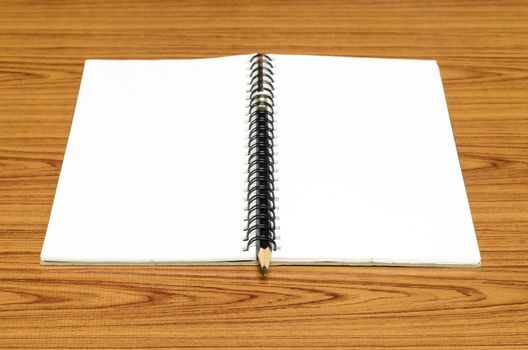 notebook and pencil on wood background