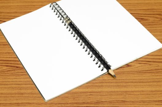 notebook and pencil on wood background