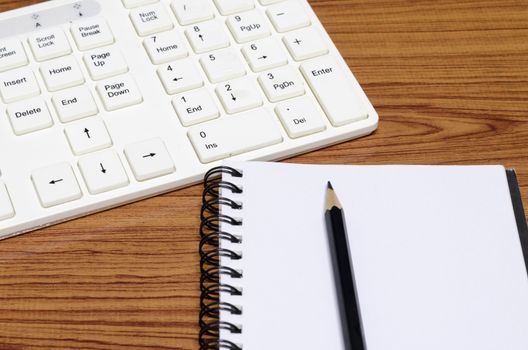 keyboard computer with notebook and pencil