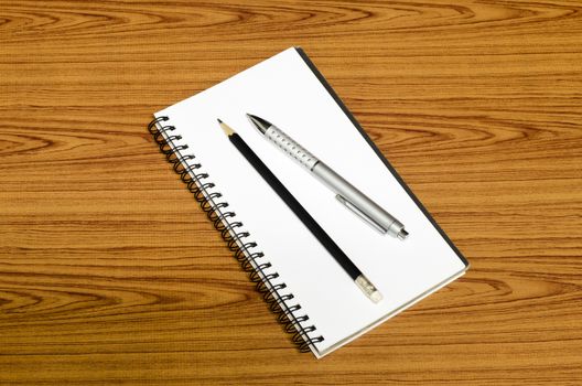 notebook pen and pencil on wood background