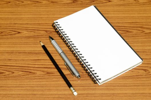 notebook pen and pencil on wood background