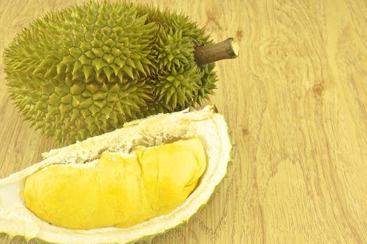 Green durian ripe and part with spikes on wood background.