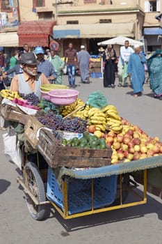 Man pushing a cart laden with fresh fruit to the market in the ancient town of Taroudant in Morocco.