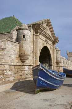 Small wooden fishing boat on the dockside inside the historic harbour of Essaouira in Morocco.