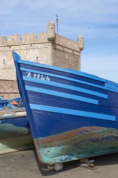 Small wooden fishing boat on the dockside inside the historic harbour of Essaouira in Morocco.