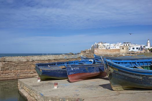 Small wooden fishing boats on the dockside inside the historic harbour of Essaouira in Morocco.