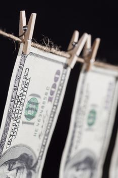 Hundred Dollar Bills Hanging From a Clothesline on a Dark Background.