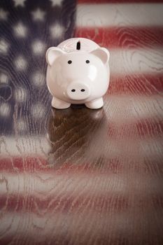 Piggy Bank with an American Flag Reflection on Wooden Table.