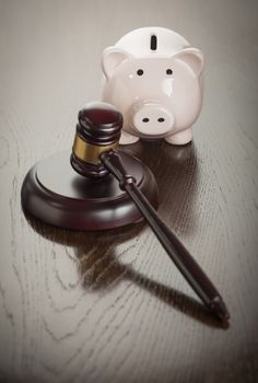 Gavel and Piggy Bank on Reflective Wooden Table.