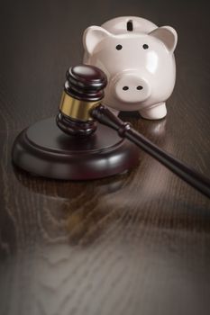 Gavel and Piggy Bank on Reflective Wooden Table.