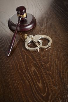 Gavel and Pair of Handcuffs on Wooden Table.