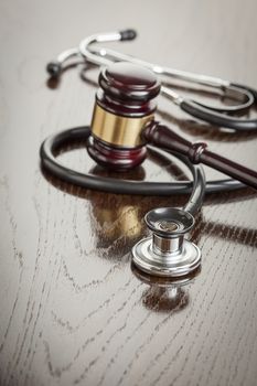 Gavel and Stethoscope on Reflective Wooden Table.