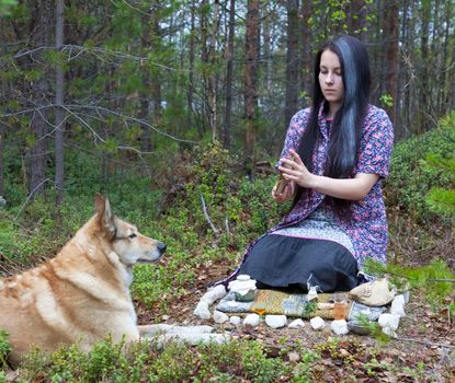 Beautiful girl witch prepares witchcraft the drug in the woods. Near a huge dog 

