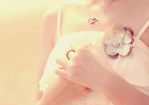 Close up of bride's hands with accessory for dress, retro filter effect