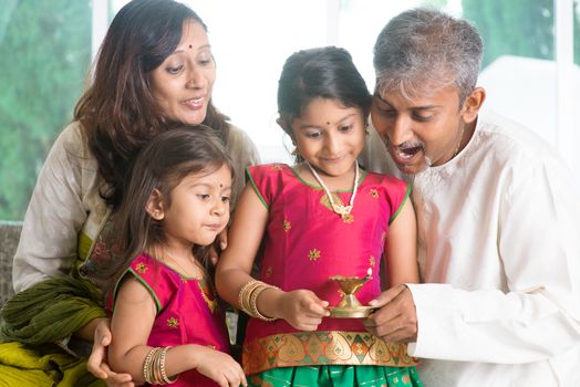 Indian family in traditional sari celebrate diwali or deepavali at home, little girl hands holding oil lamp with father indoor.