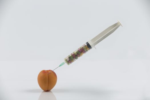 Female menopause and sexual disease metaphor: apricot and syringe with pills meaning cosmetic and health treatment for female ageing
