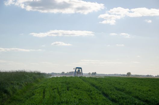 Tractor spray field with chemicals and man with metering tool in agriculture field and evening sunlight.