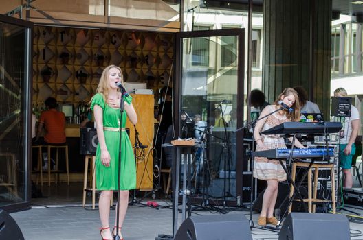 VILNIUS, LITHUANIA - MAY 18: young blonde girl sing to the microphone and friend play with a synthesizer. Street music festival on May 18, 2013 in Vilnius.