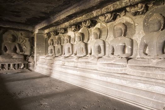 Seven images of Buddha in meditation carved out of rock inside a Buddhist rock cave (Teen Daal). Cave number 12, Ellora Caves, near Aurangabad, India. 7th - 8th Century AD