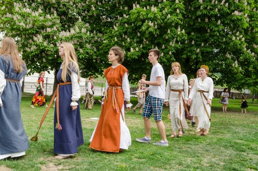 VILNIUS, LITHUANIA - MAY 18: young folklorists with national costumes singing stand in circle in the park to the chestnut on May 18, 2013 in Vilnius