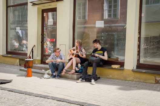 VILNIUS, LITHUANIA - MAY 18: three young street musicians singing and plays with instruments on the street on May 18, 2013 in Vilnius.